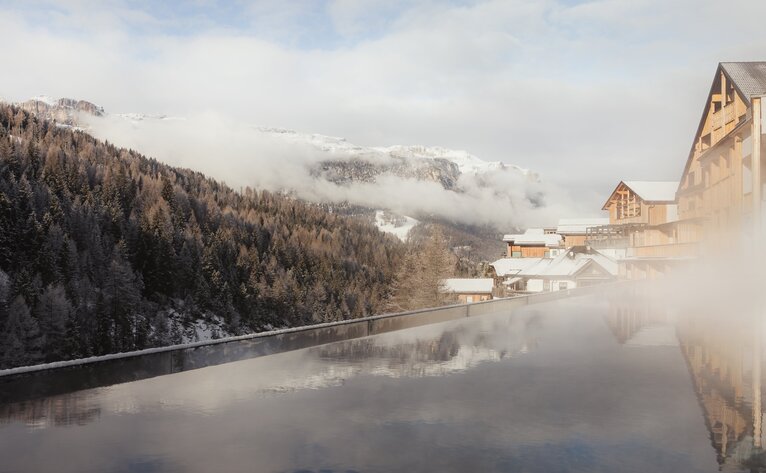 Frozen alpine lake with snow-covered mountains at Aman Rosa Alpina resort, Italy.