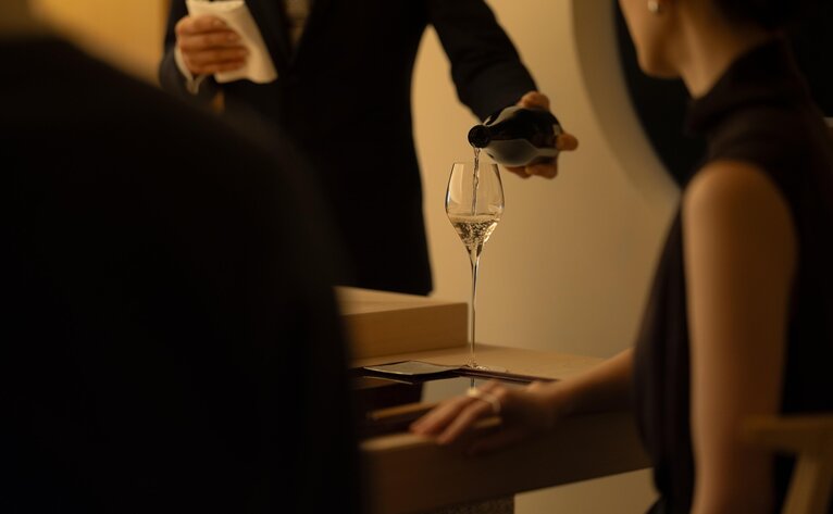 Hands reaching towards a glowing lantern at Aman Tokyo.