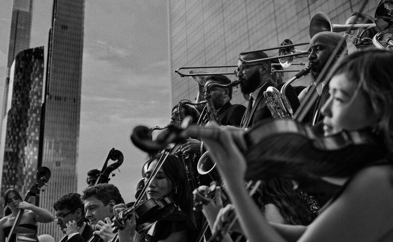 Festive celebration at Aman New York with guests gathering outdoors in winter light, black and white photograph.