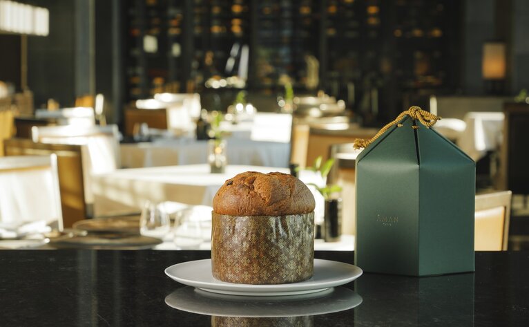 Panettone cake displayed on a dining table at Aman Tokyo, with table settings and candlelight in the background.