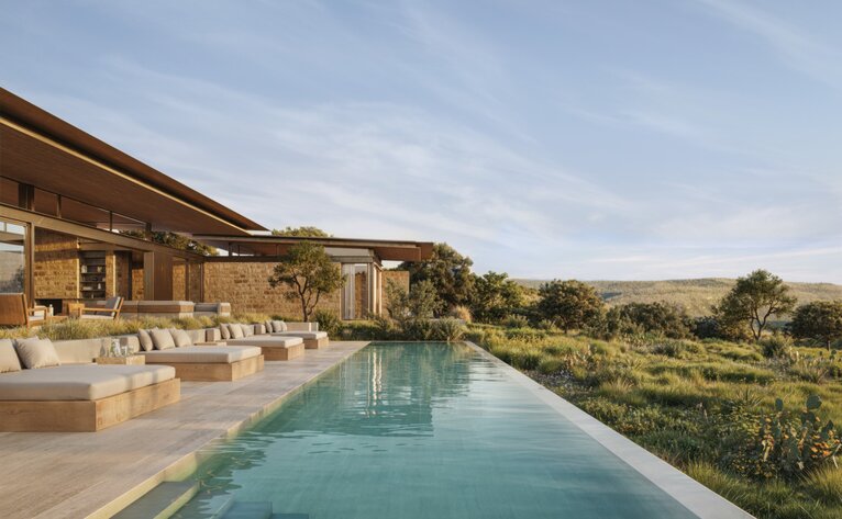 Pool terrace at Amansanu overlooking rolling landscape at sunrise.