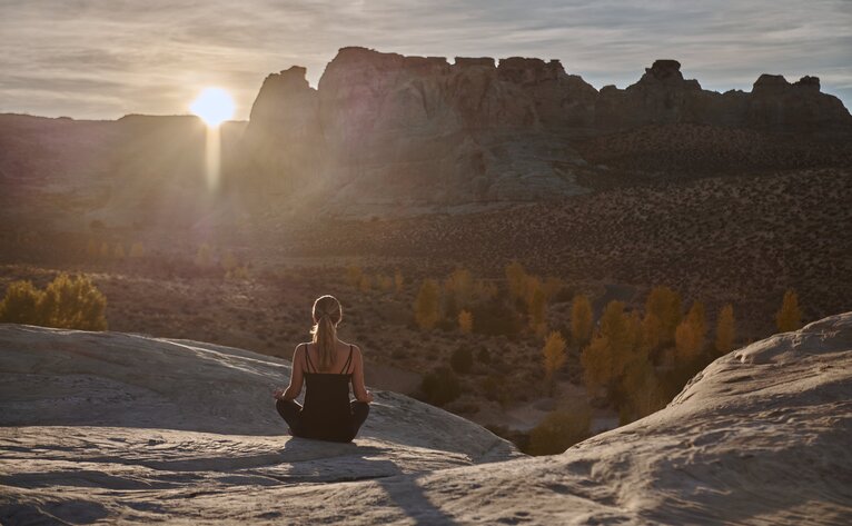 Woman practising yoga at sunrise overlooking desert landscape at Amangiri.