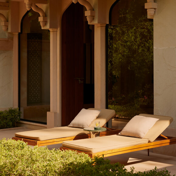 Garden Haveli Suite with cushioned seating area overlooking landscaped grounds at Amanbagh, India.
