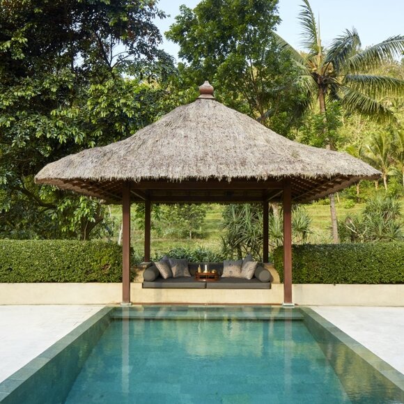 Menoreh Pool Pavilion at Amanjiwo, Indonesia, with thatched roof overlooking a still plunge pool and verdant surroundings.