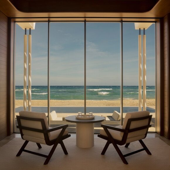 Two mid-century chairs face expansive ocean views through floor-to-ceiling windows at Amanvari beachfront casita.