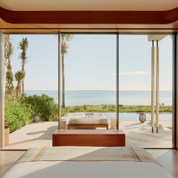 Amanvari resort accommodation with expansive windows framing ocean views and coastal landscape.