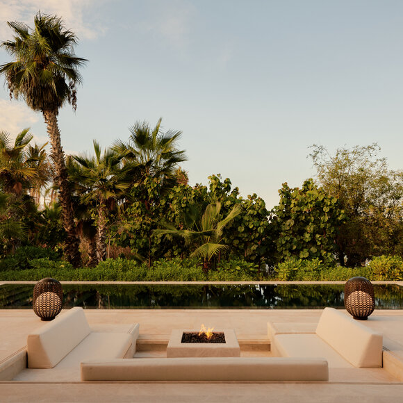 Sunken seating area with stone spheres overlooking gardens and palm trees at Amanvari resort.