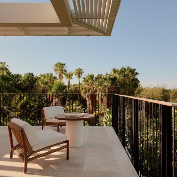Terrace at Horizon Casita with views across Amanvari's gardens towards mountains, wooden chair in foreground.