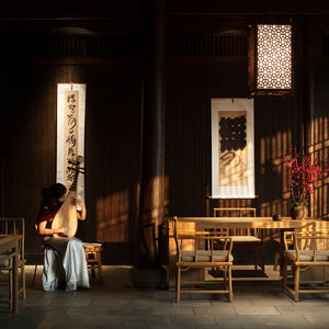 A guest in the spa relaxation area at Amanfayun, with illuminated architectural screens and wooden furnishings.