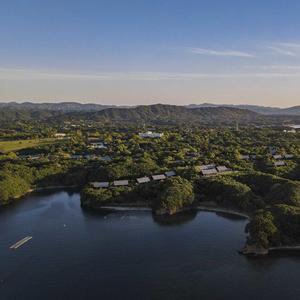 Aerial view of Amanemu resort nestled amongst forested hills and waterside landscape in Japan.
