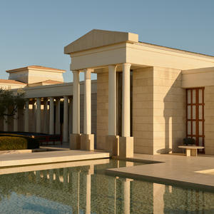 Amanzoe resort exterior with classical pavilion and reflecting pool at sunset, Greece.