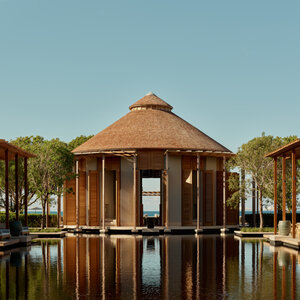 Main bar at Amanyara overlooks the ocean, with thatched roof and wooden structure reflected in still water.