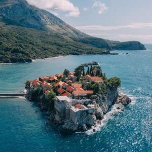 Aerial view of Sveti Stefan island with terracotta-roofed buildings surrounded by turquoise Adriatic waters, Montenegro.