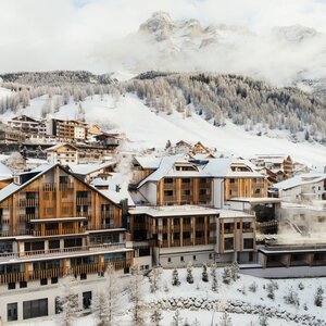 Aman Rosa Alpina exterior with snow-covered Dolomite peaks and Alpine village landscape in winter.