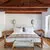 Deluxe Cottage principal bedroom at Aman Sveti Stefan with twin beds and exposed wooden beams.