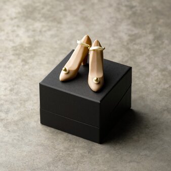 Pair of gold chocolate shoes displayed on black box at Aman Tokyo's La Patisserie.