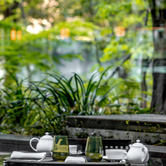 Caffetteria del Aman Tokyo con vasetti di piante e giardino sullo sfondo.