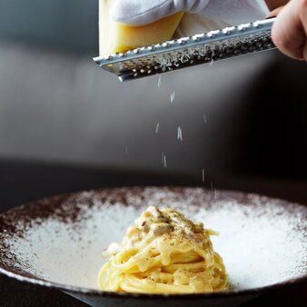 Plated carbonara at Aman Tokyo being finished with grated cheese.