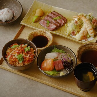 Hanami-Gozen dining spread at Aman Tokyo, featuring seasonal dishes and sashimi on wooden board.