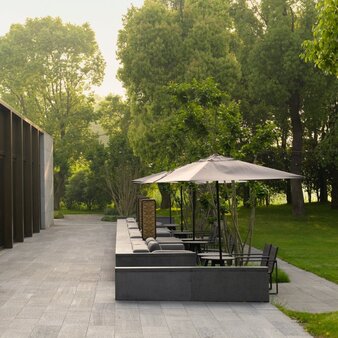 养云安缦度假村户外餐饮区，设有遮阳伞和座位，周围绿树成荫。