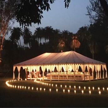 Amanbagh's illuminated event pavilion at dusk, surrounded by candlelit pathways and trees.