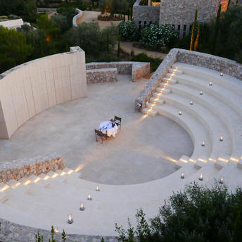 Aerial view of Amanzoe's amphitheatre with curved stone seating and two figures in the centre.