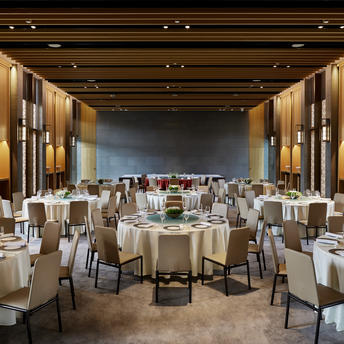 Ballroom at Amanyangyun set for a celebration with round tables, cream chairs, and warm lighting.