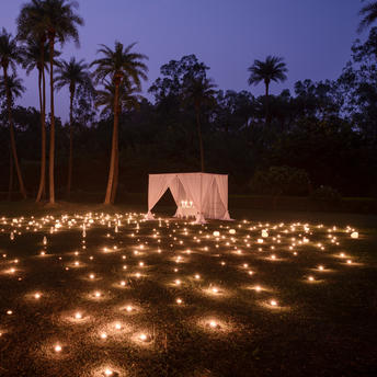 Candlelit courtyard at dusk with palm trees surrounding a pavilion at Amanbagh.