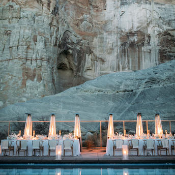 安缦奇岭度假村露天餐饮区，背靠沙岩峭壁，白色座椅整齐排列于红砂岩平台上。