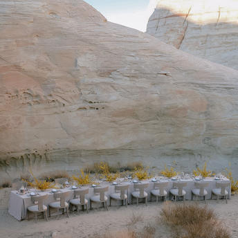 Outdoor dining table set against dramatic desert cliffs at Amangiri resort.
