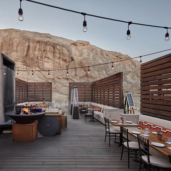 安缦奇岭度假村的篝火休闲区，沙漠山景背景下设有木质座椅和取暖设施。