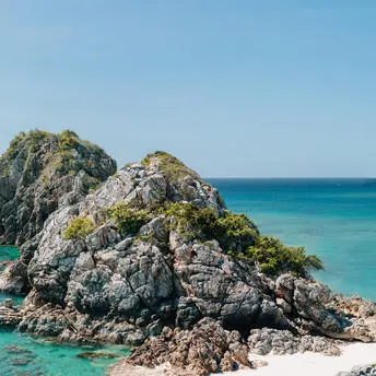 Amanpulo 리조트의 부두 광장에서 본 암초로 둘러싸인 바위섬과 맑은 청록색 바다.