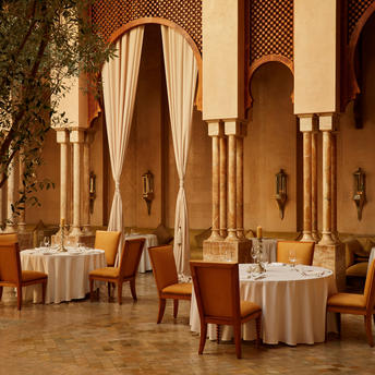 Amanjena dining venue with arched doorways, warm terracotta tones, and intimate table settings beneath Moroccan architecture.