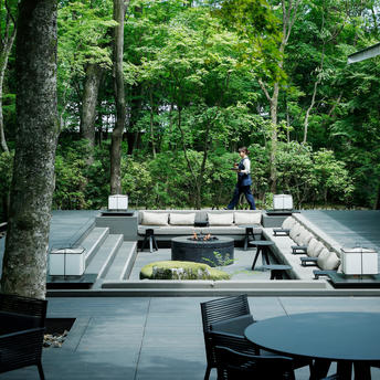 Terrazza del giardino presso la resort Aman Kyoto, con vasche d'acqua e sedute circondate da alberi.