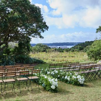 アマネムのパビリオンウェディング会場で、木製のベンチと白い花で装飾された屋外スペース。