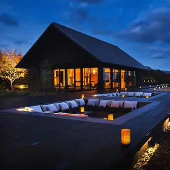Sunken terrace at dusk with seated pavilion at Amanemu resort, warm lighting reflecting on water channels.