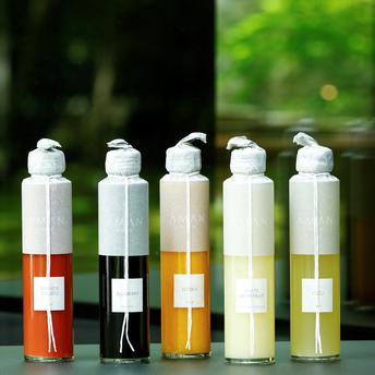 Five glass bottles of Aman Kyoto juice in assorted flavours displayed in a row.