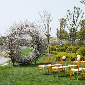 Wooden chairs arranged on a lawn at Amanyangyun, with manicured gardens and flowering trees beyond.