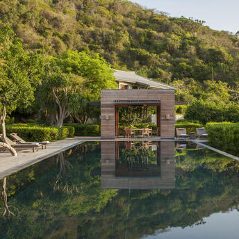 Bay View Residence at Amanoi with reflecting pool and forested Vietnamese hillside backdrop.