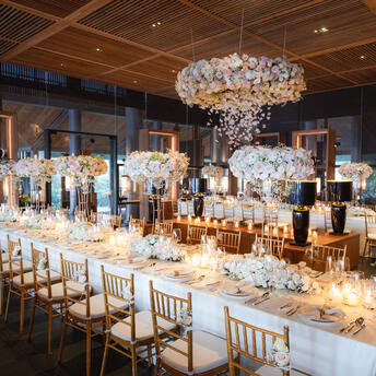 Amanoi's Glass Hall set for an elegant dining event, with long tables, crystal chandelier, and candlelit centrepieces.
