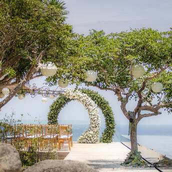 Ocean-facing plunge pool with wooden loungers beneath curved trees at Amanoi, Vietnam.
