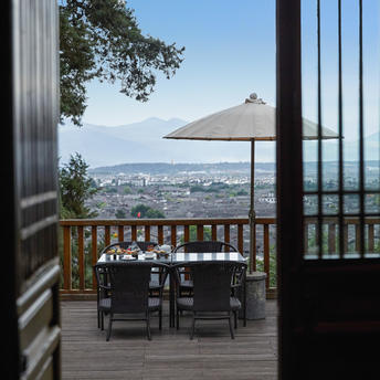 Wooden deck with dining chairs and parasol overlooking mountains at Amandayan tea house.