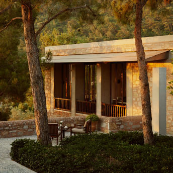 Amanruya's wine lounge terrace with wooden pavilion nestled among pine trees at dusk.
