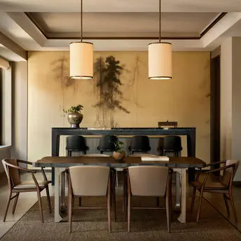 Salle à manger de la Suite Aman à Aman New York, avec table en bois, chaises et buffet noir.