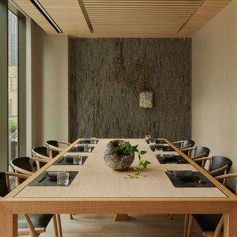 Sala de reuniones privada con mesa de madera y pared de piedra en Aman New York.