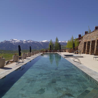 Rectangular swimming pool at Amangani with mountain views and sun loungers on the surrounding terrace.