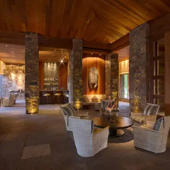 Zinc Bar at Amangani with warm lighting, stone columns, and contemporary seating.