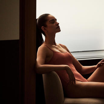 Woman relaxing in an armchair with a view of New York City at Aman New York.