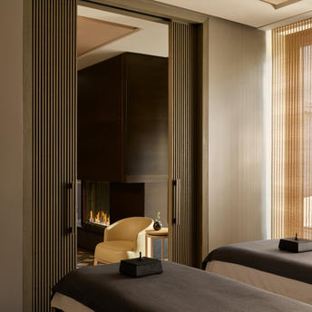 Spa treatment room at Aman New York with arched doorway and warm fireplace glow.
