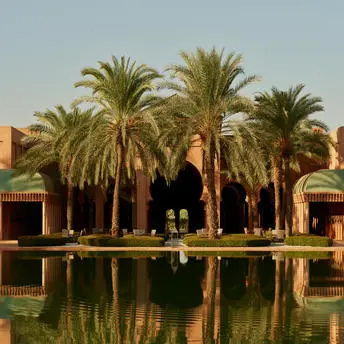 Central basin event space with palm trees and reflecting water at Amanjena resort, Morocco.